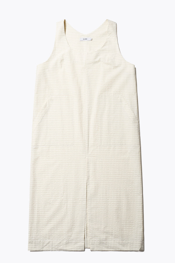 Long-length Forces Pinafore Dress in Ecru Beige Kloke designed soft seersucker premium cotton . Relaxed fit with a deep rounded neckline, front patch pockets, and a front split for ease of movement. Available in 5 sizes.