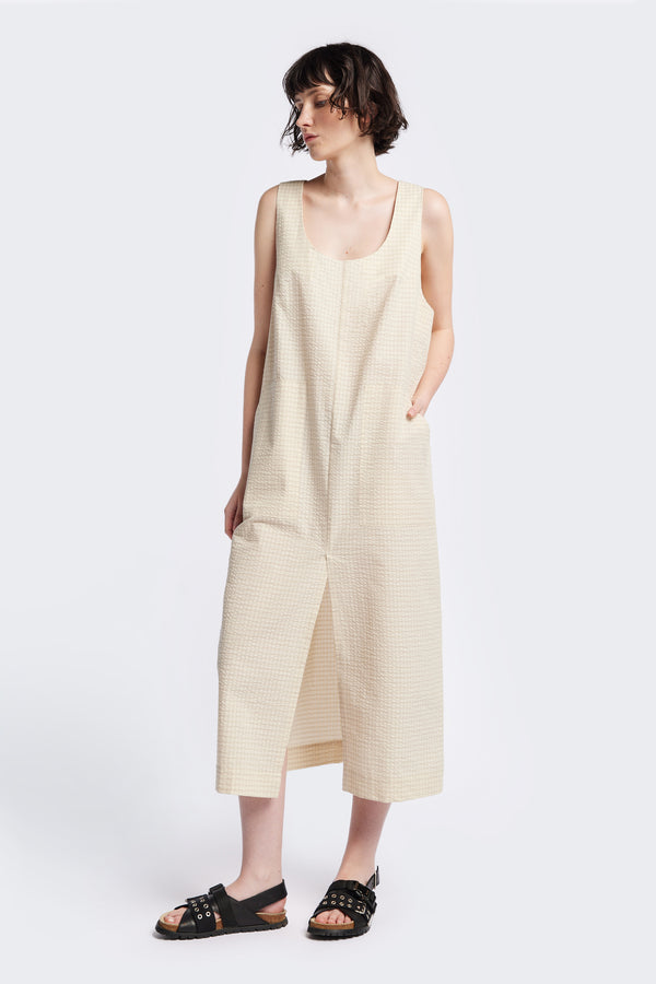 Long-length Forces Pinafore Dress in Ecru Beige Kloke designed soft seersucker premium cotton . Relaxed fit with a deep rounded neckline, front patch pockets, and a front split for ease of movement. Available in 5 sizes.