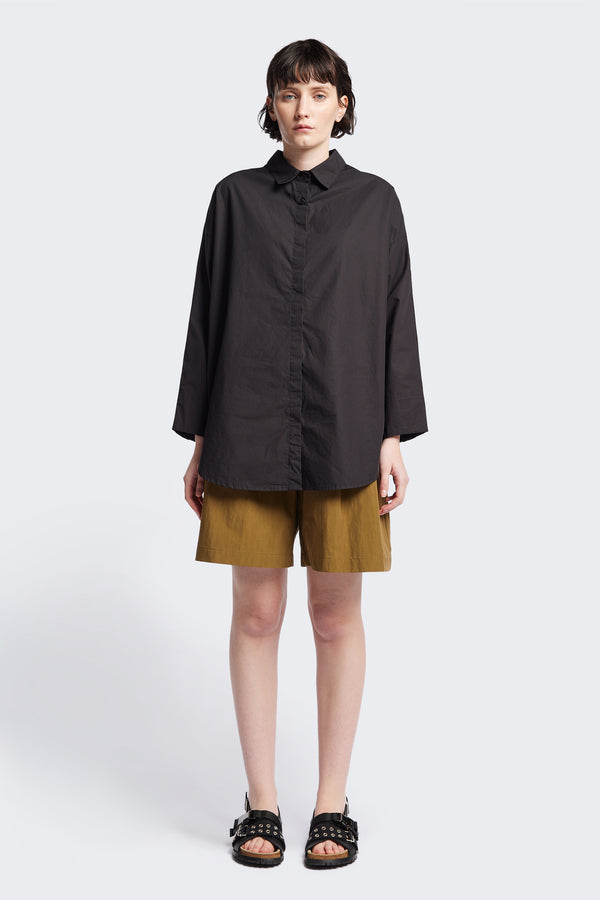 Front of Kestrel Shirt Black – relaxed long sleeve shirt with back button placket and scoop hemline, worn by model. Available in XXS, XS, S, M, L