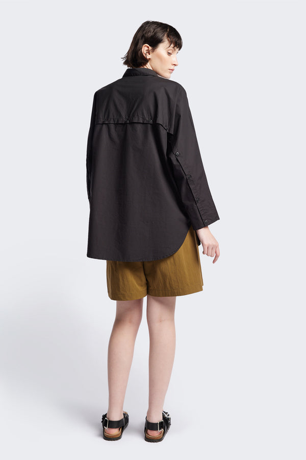 Back of Kestrel Shirt Black – relaxed long sleeve shirt with back button placket and scoop hemline, worn by model. Available in XXS, XS, S, M, L