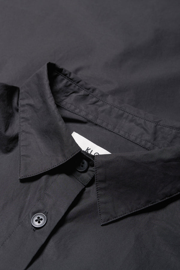 Details of Kestrel Shirt Black – relaxed long sleeve shirt with back button placket and scoop hemline, worn by model. Available in XXS, XS, S, M, L