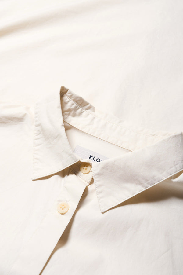 Details of the Kestrel Shirt Ecru – relaxed long sleeve shirt with back button placket and scoop hemline, worn by model. Available in XXS, XS, S, M, L