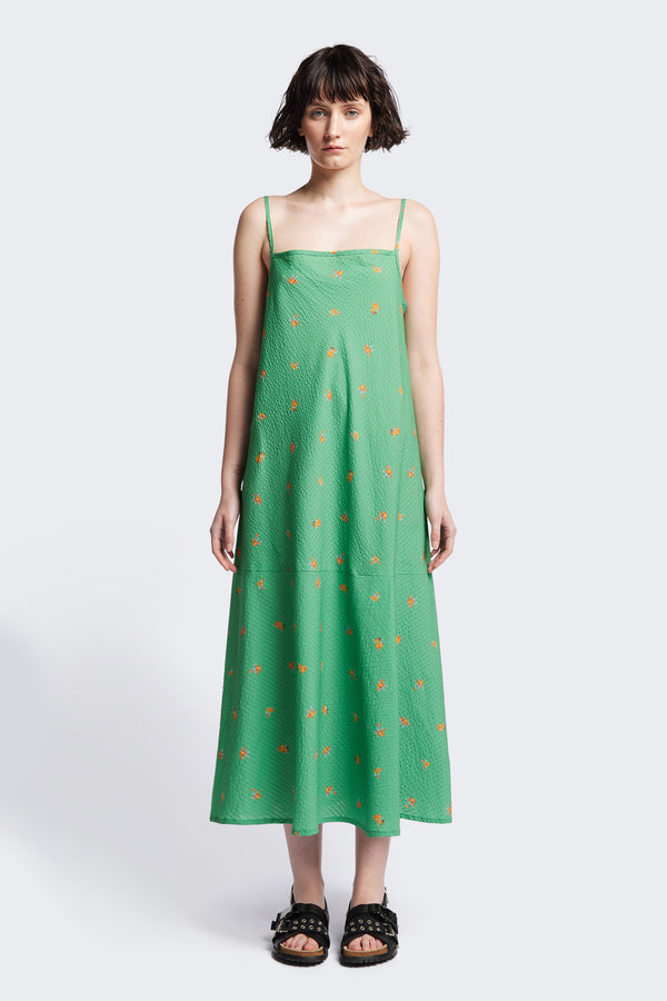 The Natant Dress in green floral, a Maxi-length Natant Dress with adjustable thin straps, a straight neckline, and a bias-cut silhouette, made from lightweight printed seersucker. Available in 5 sizes.