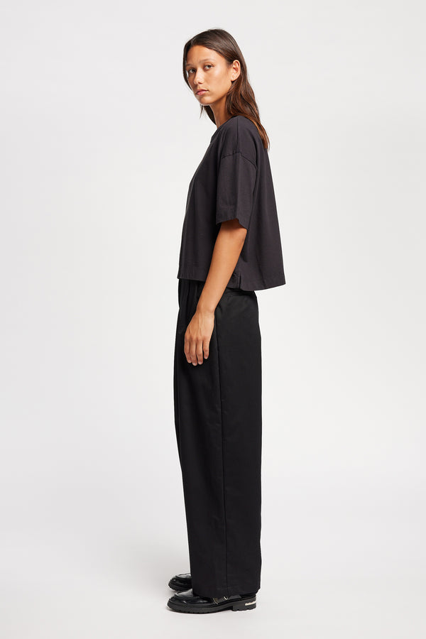 Side of Model wearing Obelisk Tee in Jet Black, showcasing oversized silhouette and dropped shoulders