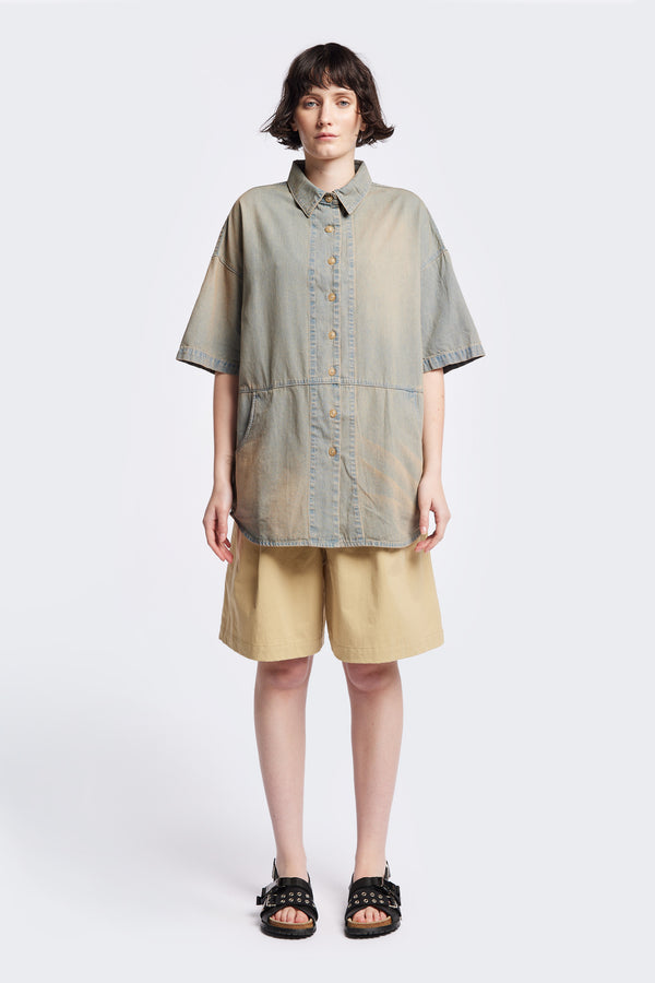 Front of the Province Oversized short-sleeve denim shirt with feature front scoop pockets, in a blue fade with a slight pink tint. Available in 5 sizes.