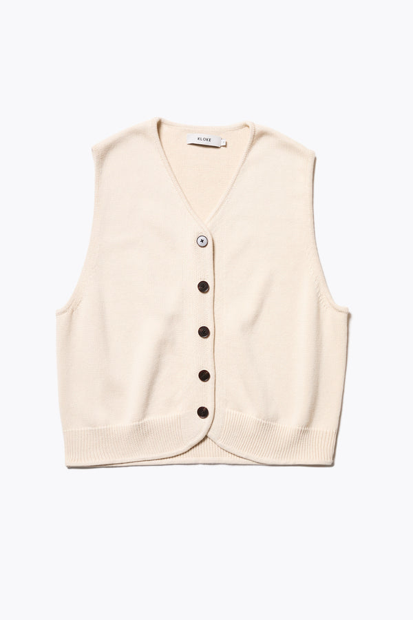 The Ritual Vest in Ecru Beige soft cotton rib, featuring a shallow V-neckline and centre front button placket. A versatile trans-seasonal layering piece, available in 5 sizes.