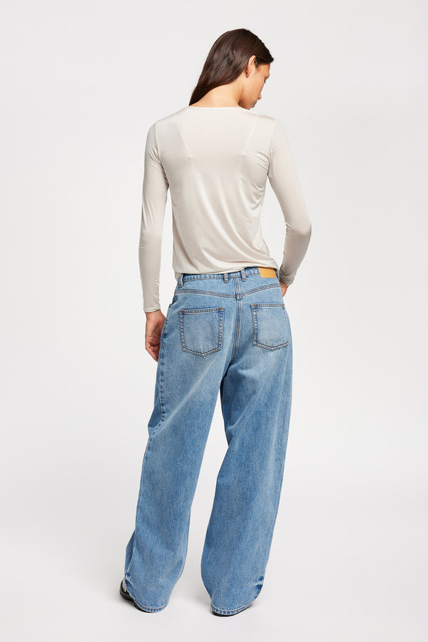 Back view of Model wearing Kloke straight-leg jeans in mid-blue Japanese denim, featuring a mid-rise waist and relaxed silhouette