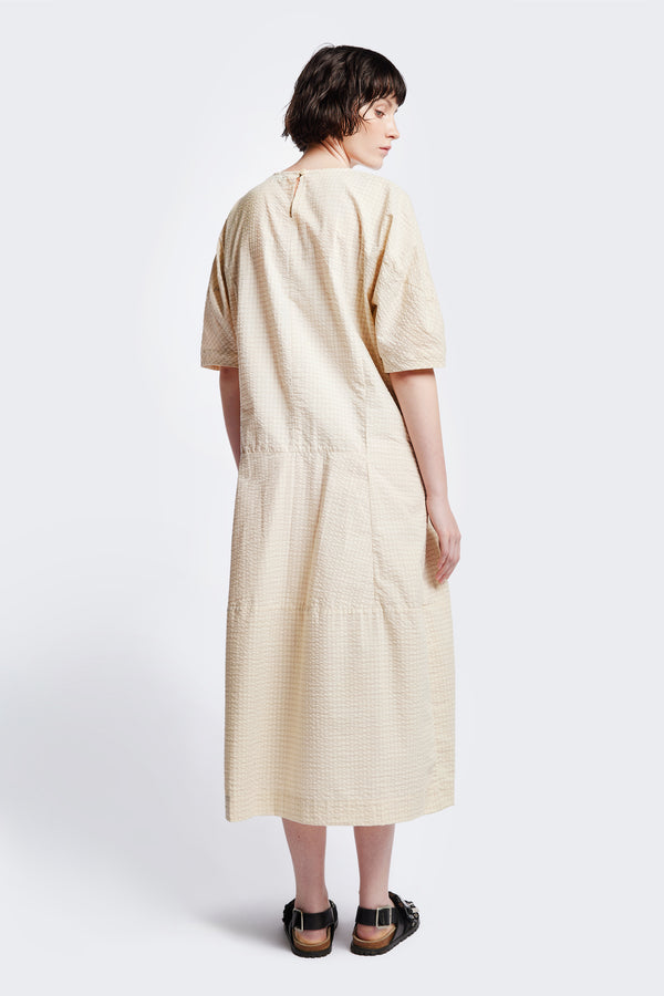 Back of The Scoria Dress in Ecru beige, a long-panelled cotton seersucker dress with voluminous sleeves, structured panel details, and a fuller skirt, perfect for an effortless summer look. Available in 5 sizes.