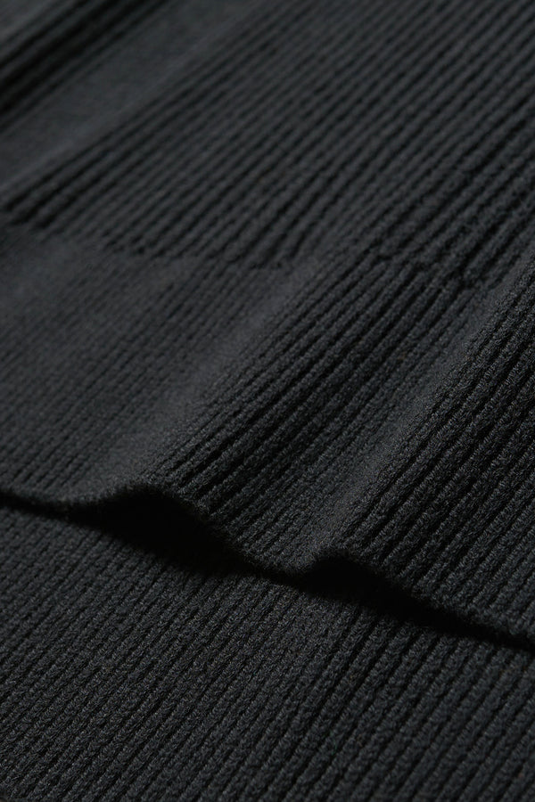 Close up fabric detail shot of black
sleeveless ribbed knit vest with side ties in merino and cotton blend