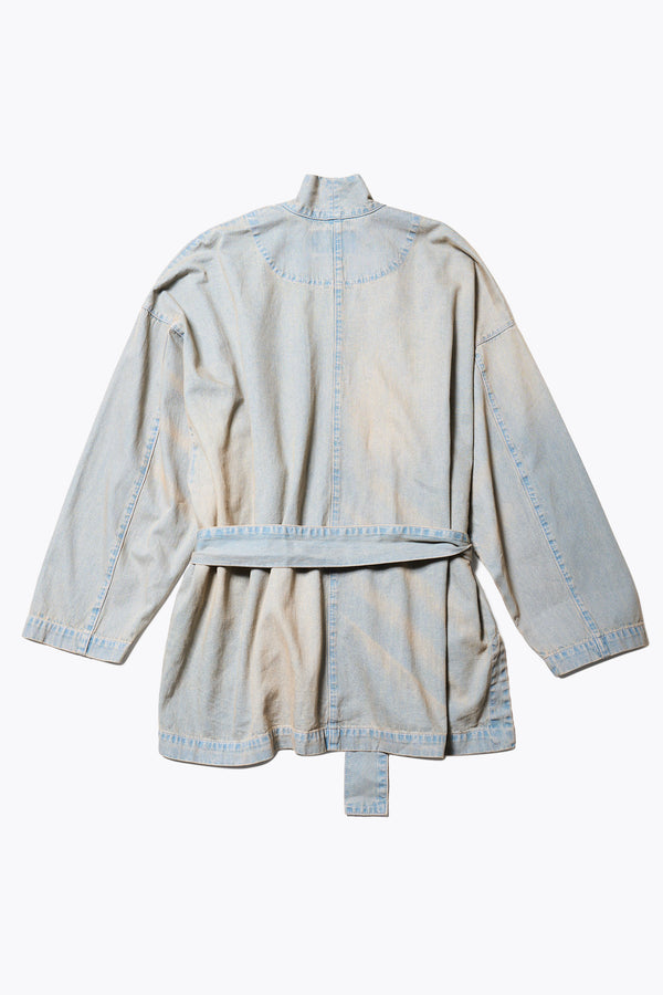 Flat Back of the unisex Subterra Wide wrap shawl collar jacket with kimono-style sleeves, crafted from cotton denim, featuring front patch pockets and a waist tie to cinch the loose silhouette. Available in 5 sizes.