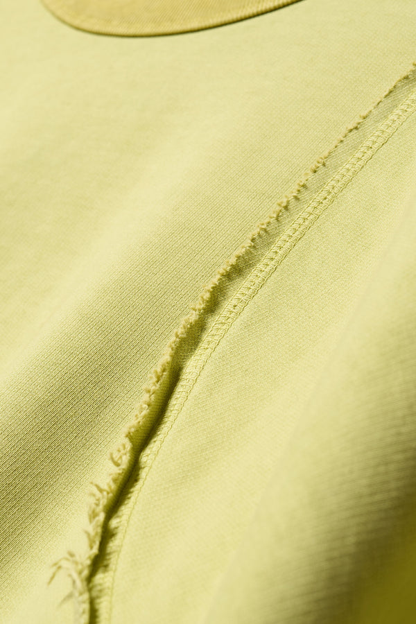 close up fabric details of Unisex format oversized crew neck sweater in chartreuse with clean panelled design and raw flat-locked seams, displayed from the front.