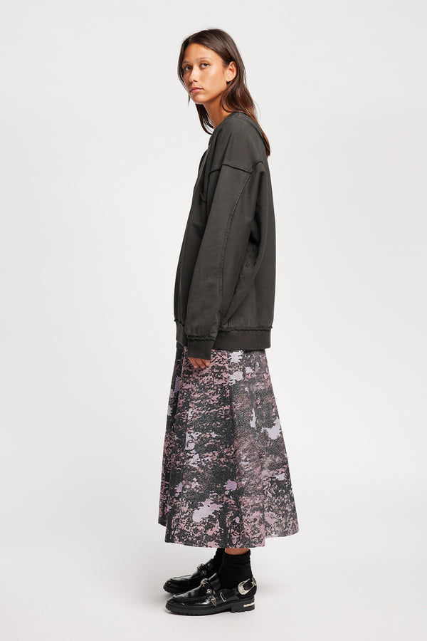 women - side of model wearing Unisex format oversized crew neck sweater in jet black with clean panelled design and raw flat-locked seams, displayed from the front.