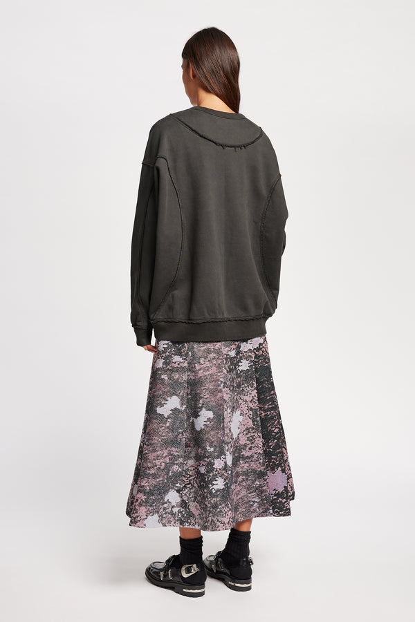 women - back of model wearing Unisex format oversized crew neck sweater in jet black with clean panelled design and raw flat-locked seams, displayed from the front.