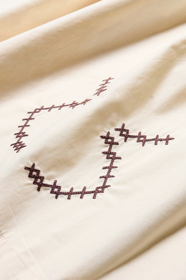 Close up embroidery details of the Ecru Universe Embroidered Skirt showcasing Arecibo-inspired motifs.