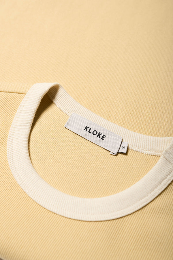 Close up of the Veil Rib Tee a slim-fit ringer tee in ribbed cotton, featuring a vintage 70's-inspired design with contrasting neckline and sleeve details. Available in 5 sizes.