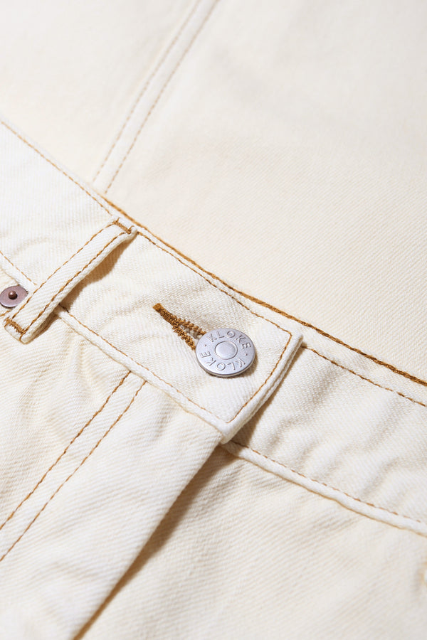 Close up of The Vivendi Skirt in ecru a Straight denim pencil skirt with a front split and midi length, crafted from 12oz Japanese denim. Available in 6 sizes.