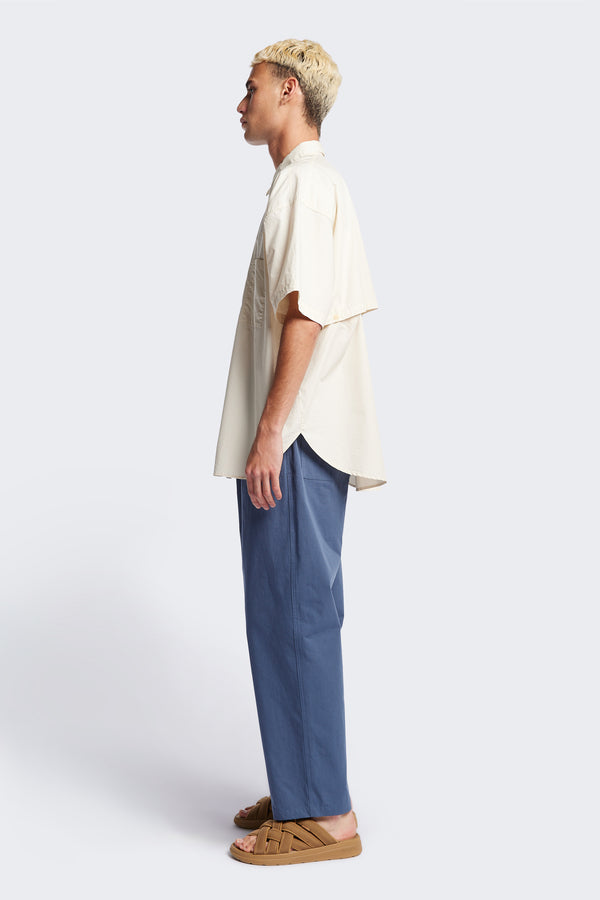 (men) Relaxed loose-fitting boxy short-sleeve shirt with back button placket, scoop hemline, and chest patch pockets, crafted in lightweight cotton poplin. Available in 5 sizes.