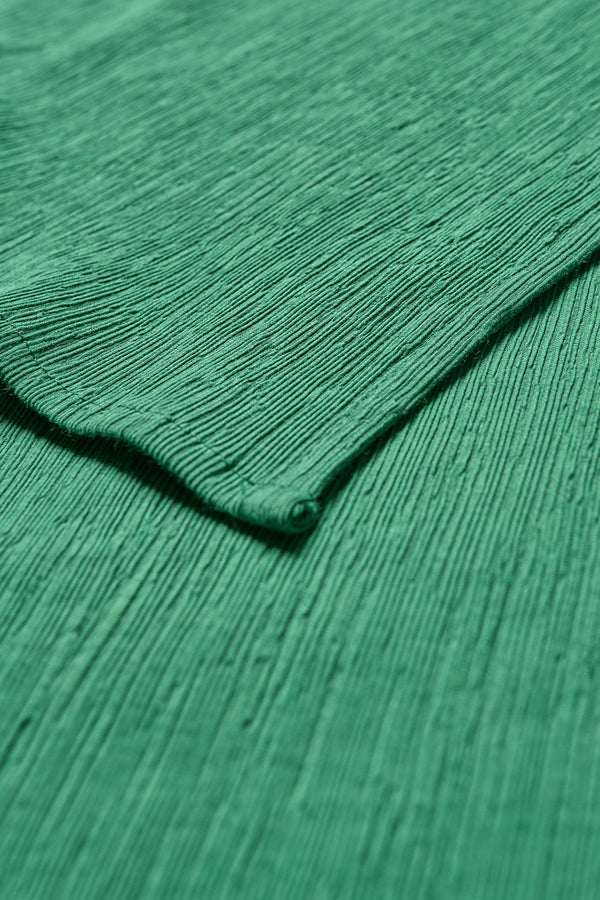 Aeon Crinkle Top in Green Close up fabric shot, featuring a sleeveless design, panelled bustline, high neckline, and concealed back zip. Crafted from structured crinkled crepe fabric. Available in 4 sizes.