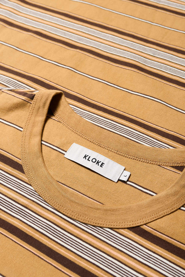 Close up details of The Attain T-Shirt in tan, a classic fit t-shirt in ticking stripe cotton jersey, featuring a rib-bound cover-stitched neckline and reinforced back. Available in 5 sizes. 