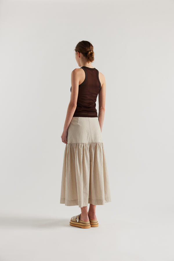 Back angle of Model in the Ecru and Black Pin Stripe Panelled cotton skirt with gathered full silhouette, wide yoke waist, and invisible back zip closure.