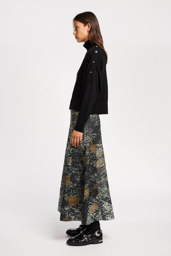 Side view of Model wearing merino wool mock neck sweater with shoulder button detail in black. 