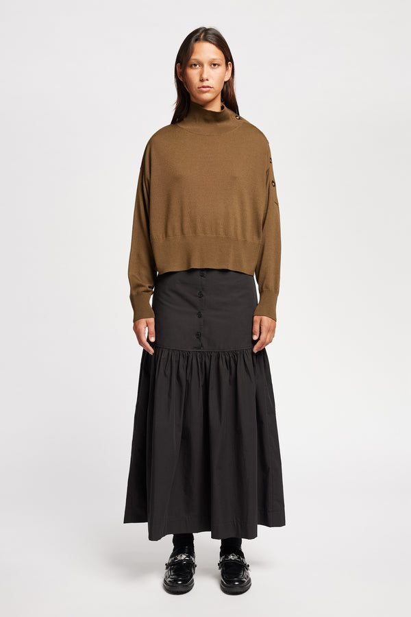 Front view of Model wearing merino wool mock neck sweater with shoulder button detail in brown. 