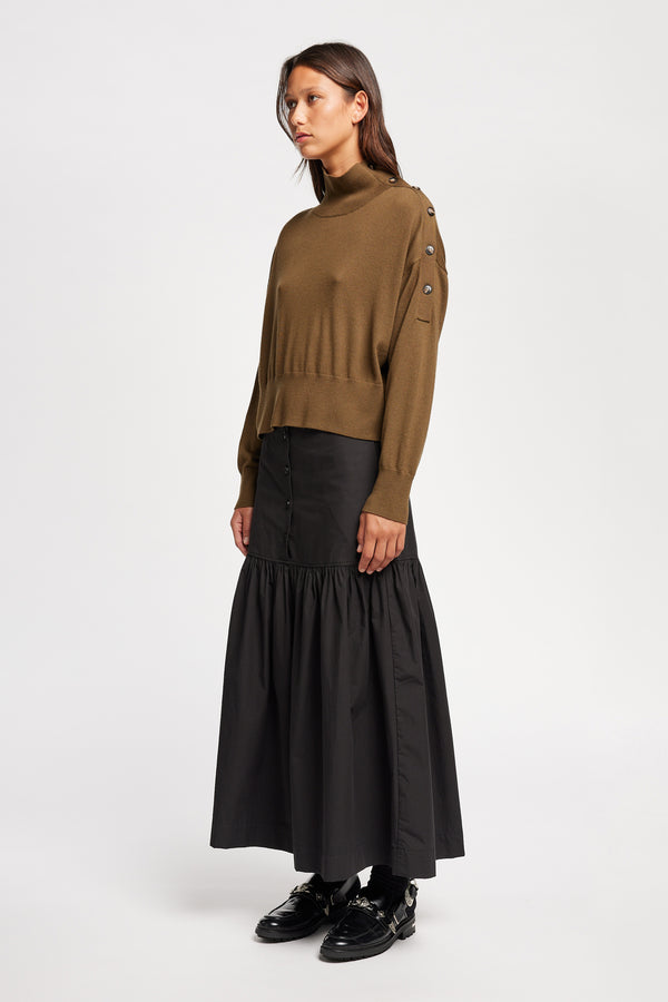Front angle view of Model wearing merino wool mock neck sweater with shoulder button detail in brown. 