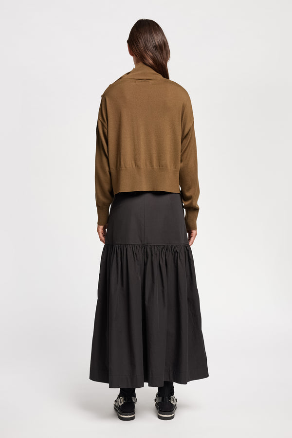 Back view of Model wearing merino wool mock neck sweater with shoulder button detail in brown. 