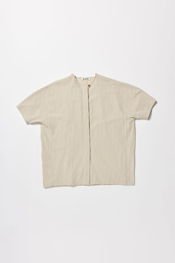 Flat front of the oversized boxy yarn-dyed cotton top with round crew neck and concealed placket in Ecru with black pin stripe. 