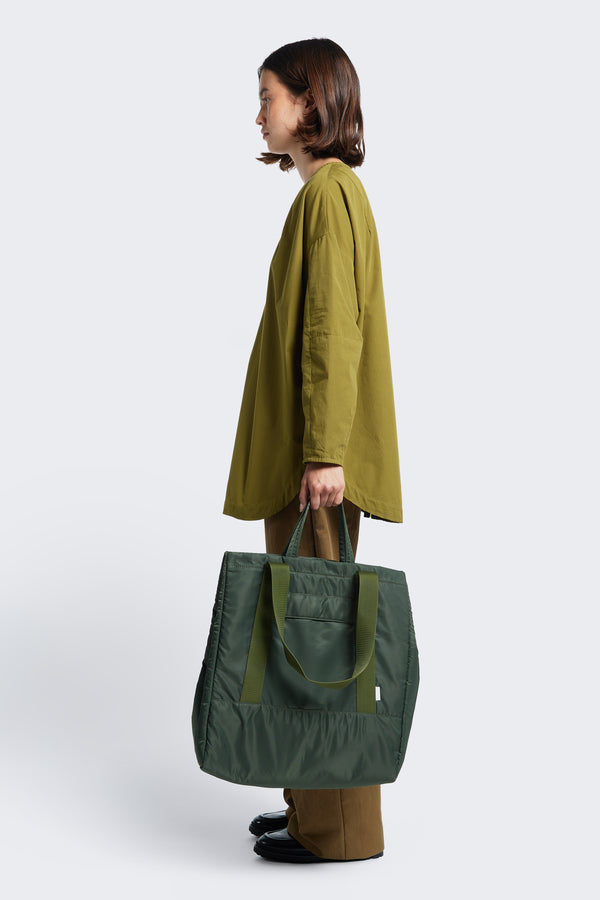 Model holds the shorter straps on the Influx Padded Bag Olive, a practical tote with four compartments including two snap-closing pockets. 