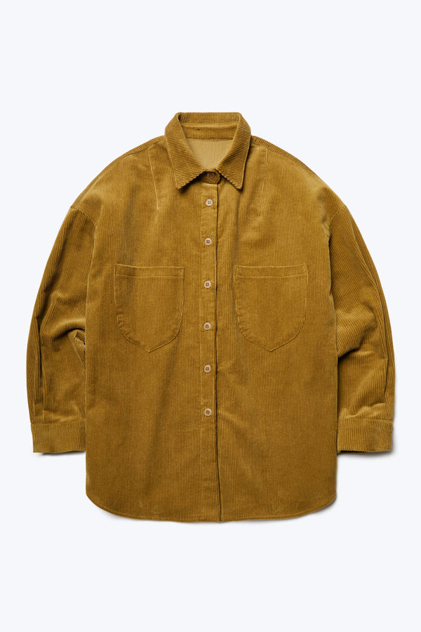 The front of the Corner Cord Shirt Golden Tan, a long sleeve, buttoned up shirt made from thick wale corduroy featuring details such as scooped patch-pockets and rounded hemline. 