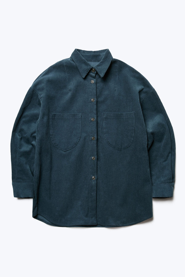 The front of the Corner Cord Shirt Petrol Blue made from thick wale corduroy featuring details such as scooped patch-pockets and rounded hemline. 