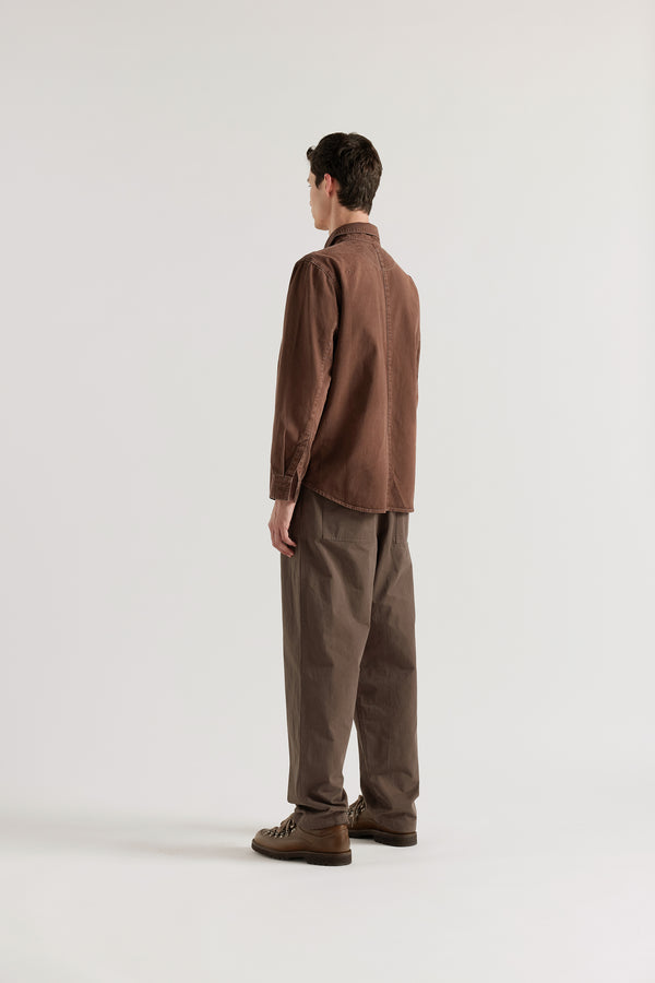 Back view of the oversized denim shirt in brown fade featuring shoulder darts and a curved hem.