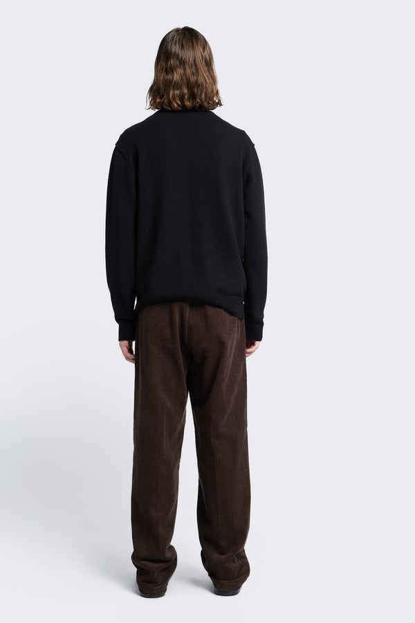 The back of the Intake Pleat Pant Chocolate Brown, a semi-tailored cord pant with a loose fit. Featuring two button-closing back pockets to keep valuables safe.