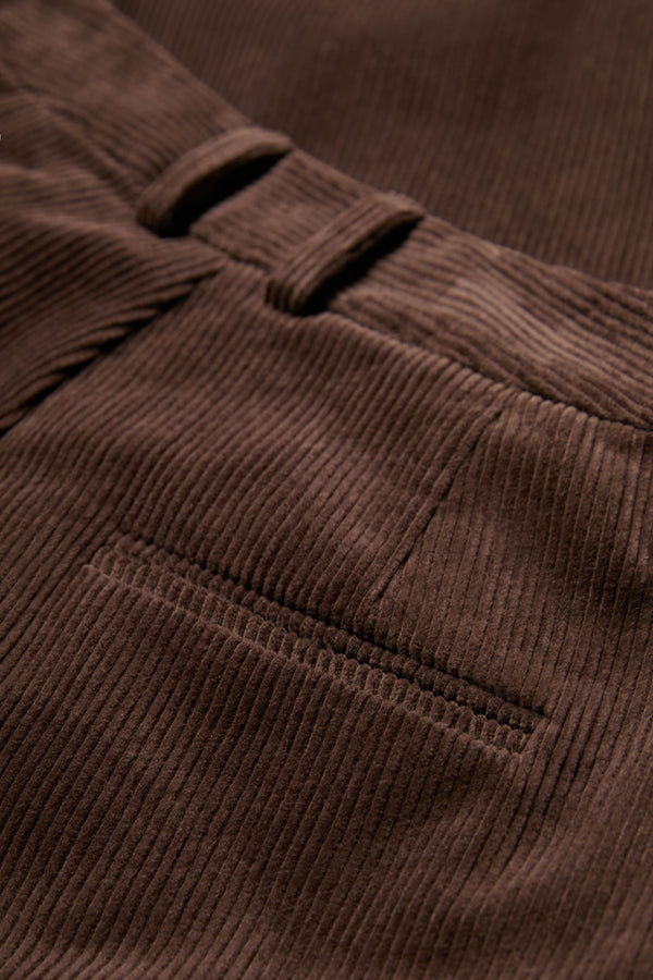 The Intake Pleat Pant corduroy fabric in Chocolate Brown with button-closing back pockets to keep valuables safe