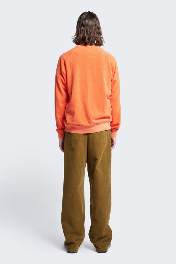 The back of the Intake Pleat Pant Golden Tan, a semi-tailored cord pant with a loose fit. Featuring two button-closing back pockets to keep valuables safe.