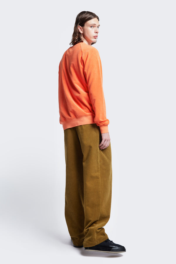 Side profile of the Intake Pleat Pant Golden Tan, a semi-tailored cord pant with a loose, double-pleated fit. Featuring side slant-pockets and two button-closing back pockets.