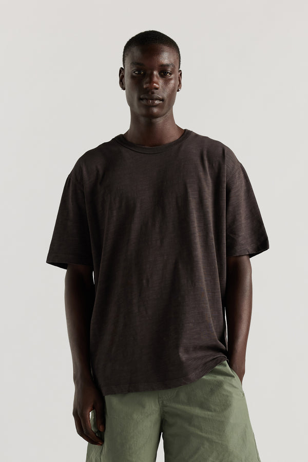 Front of model in Inverse Tee in black licorice pigment-dyed slub cotton with an oversized relaxed fit.