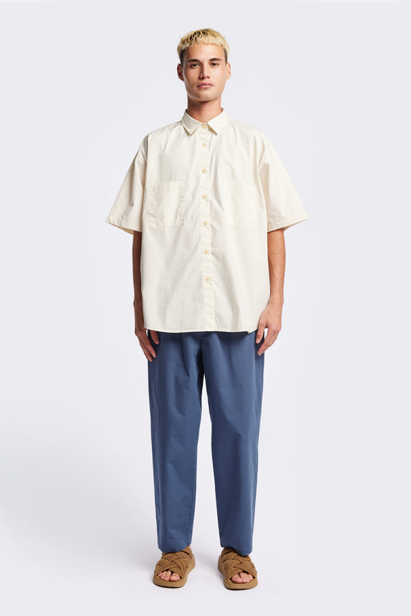 (men) Relaxed loose-fitting boxy short-sleeve shirt with back button placket, scoop hemline, and chest patch pockets, crafted in lightweight cotton poplin. Available in 5 sizes. 