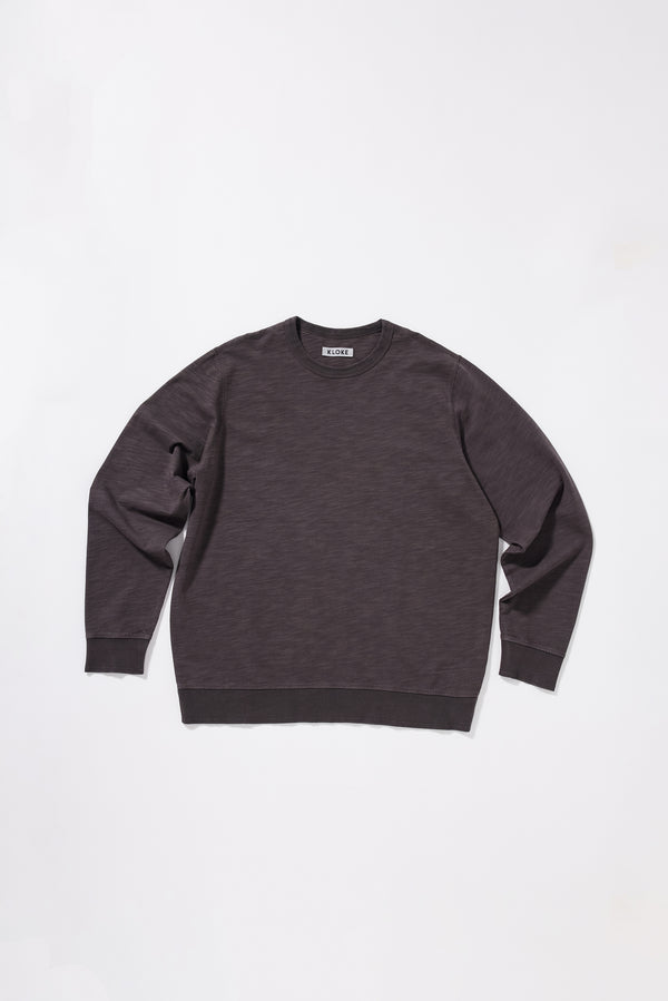 Flat front of the Relaxed long-sleeve T-shirt in washed black/ licorice pigment-dyed slub cotton with a classic crew neckline. 