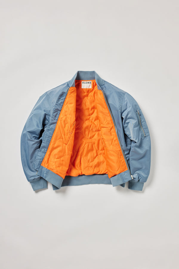 Flat front of the Grey Blue Lyric Bomber Jacket in garment-washed nylon with zip front, tonal ribbing and multiple utility pockets.
