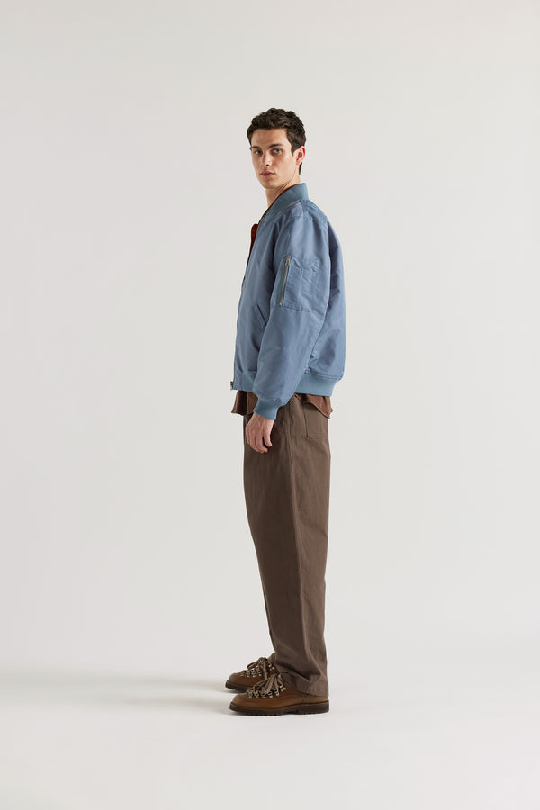 Side of model in the Grey Blue Lyric Bomber Jacket in garment-washed nylon with zip front, tonal ribbing and multiple utility pockets.