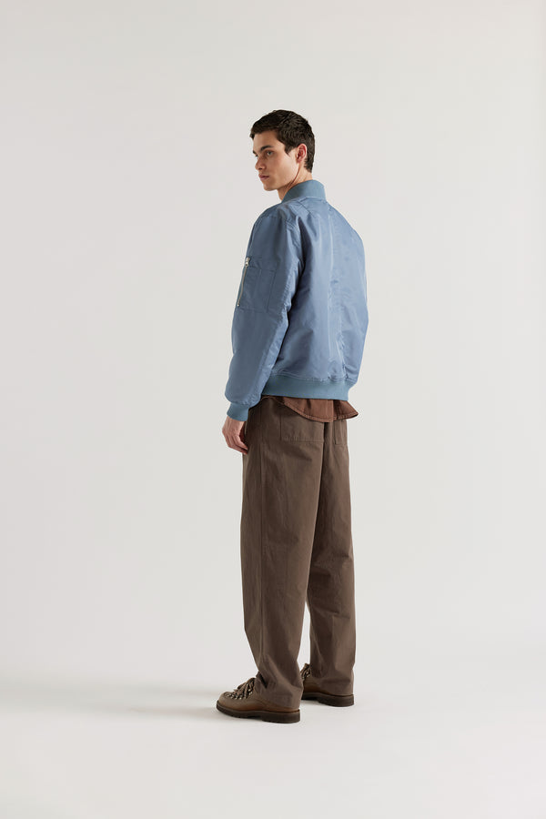 Back of model in the Grey Blue Lyric Bomber Jacket in garment-washed nylon with zip front, tonal ribbing and multiple utility pockets.
