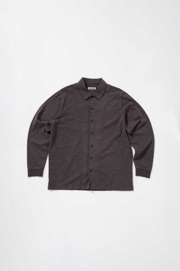 Flat front of the black licorice Shadow Jersey Shirt in pigment-dyed slub cotton with a relaxed boxy fit and button-through front.
