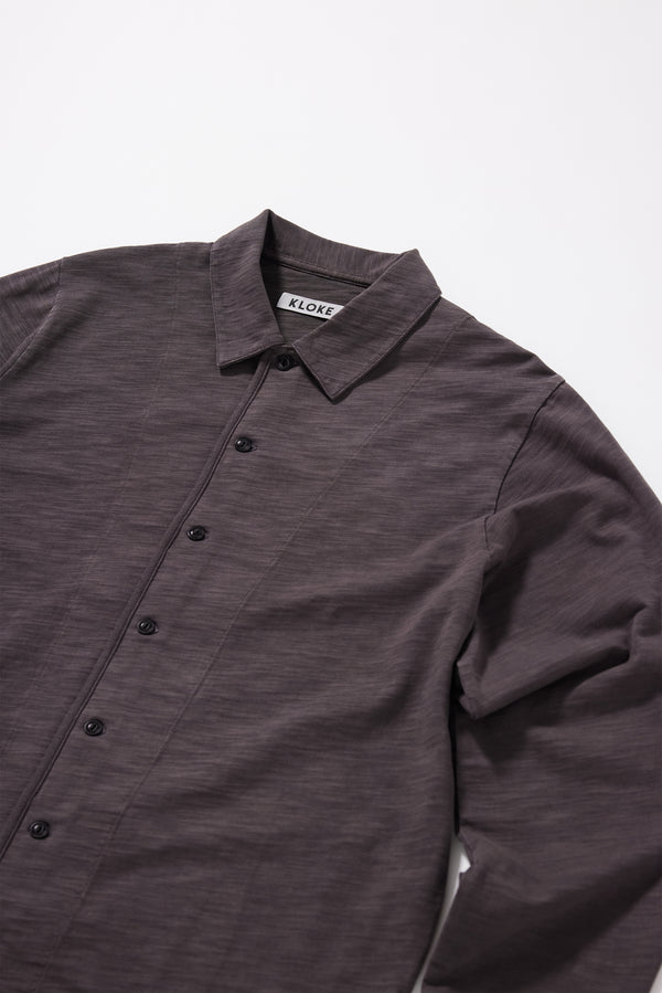 Close-up of pigment-dyed slub cotton fabric showing its textured surface and soft finish + neat collar and button-through front on the Shadow Jersey Shirt.