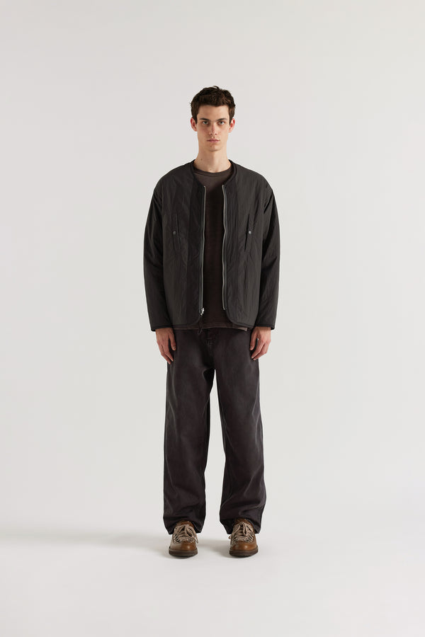 Front of the vintage black Reversible recycled nylon jacket worn plain-side out, showing a clean minimalist finish with accessible pocket detail