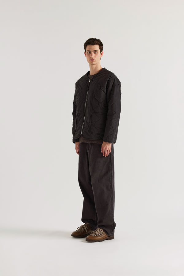 Front angle of the vintage black Reversible recycled nylon jacket shown with ripple-patterned stitching facing outward and front pockets visible