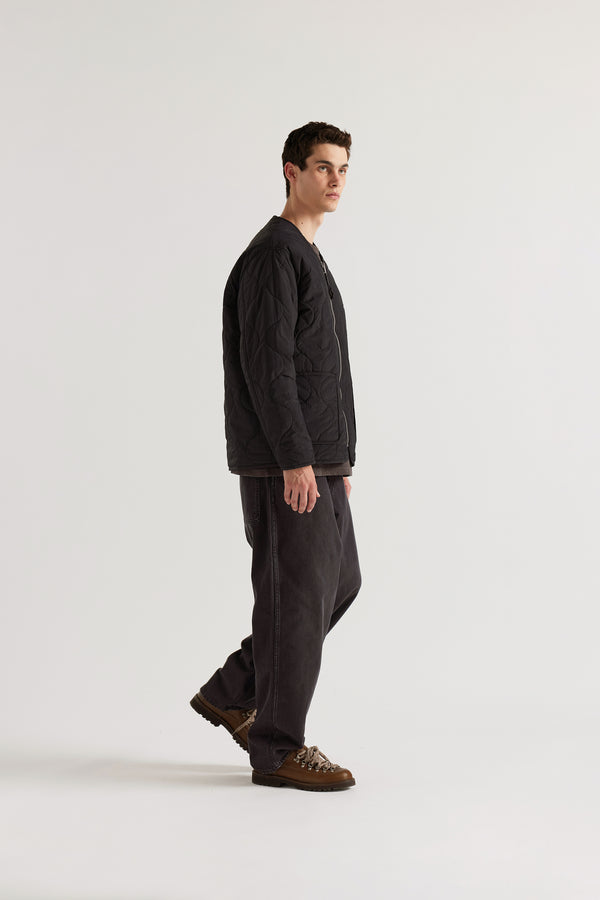 Side of the vintage black Reversible recycled nylon jacket shown with ripple-patterned stitching facing outward and front pockets visible