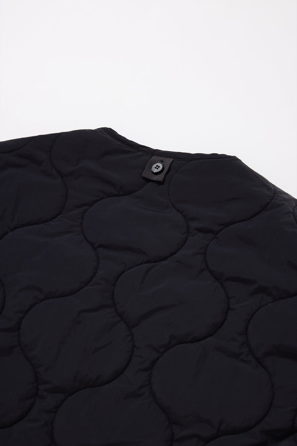 Close-up detail shot of ripple-patterned quilted stitching on recycled nylon reversible jacket. Showcasing back button to attach to parka 