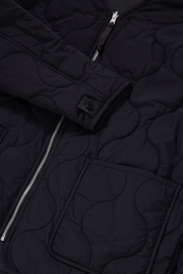 Close-up detail shot of ripple-patterned quilted stitching on recycled nylon reversible jacket. Showcasing Pocket, zip and cuff detailing. 